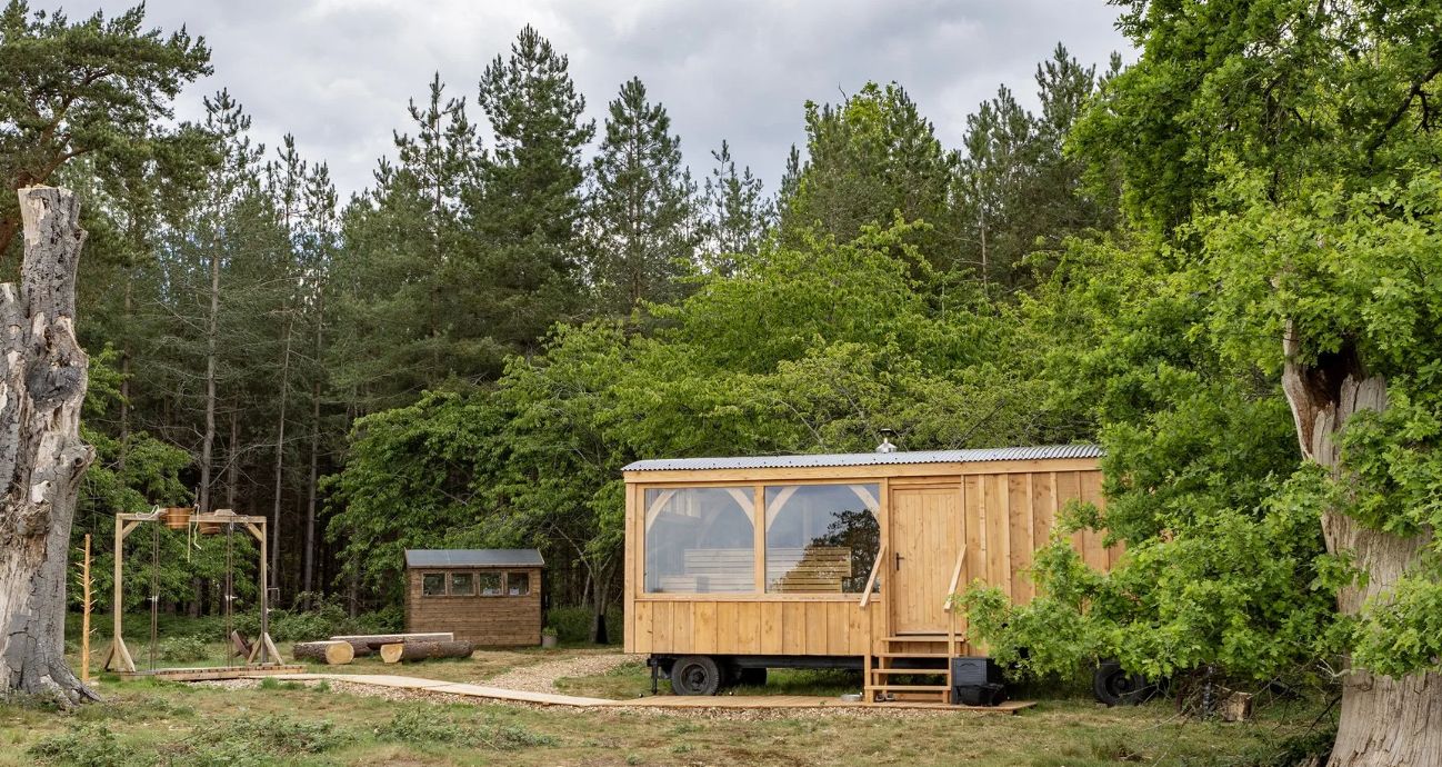 The Waggon Sauna: a timber waggon with big windows, in a clearing in the woods at the Hampton Estate